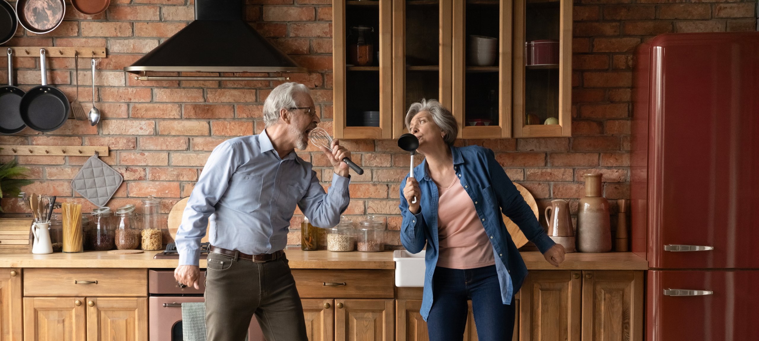 Happy Active adults singing and dancing in the kitchen